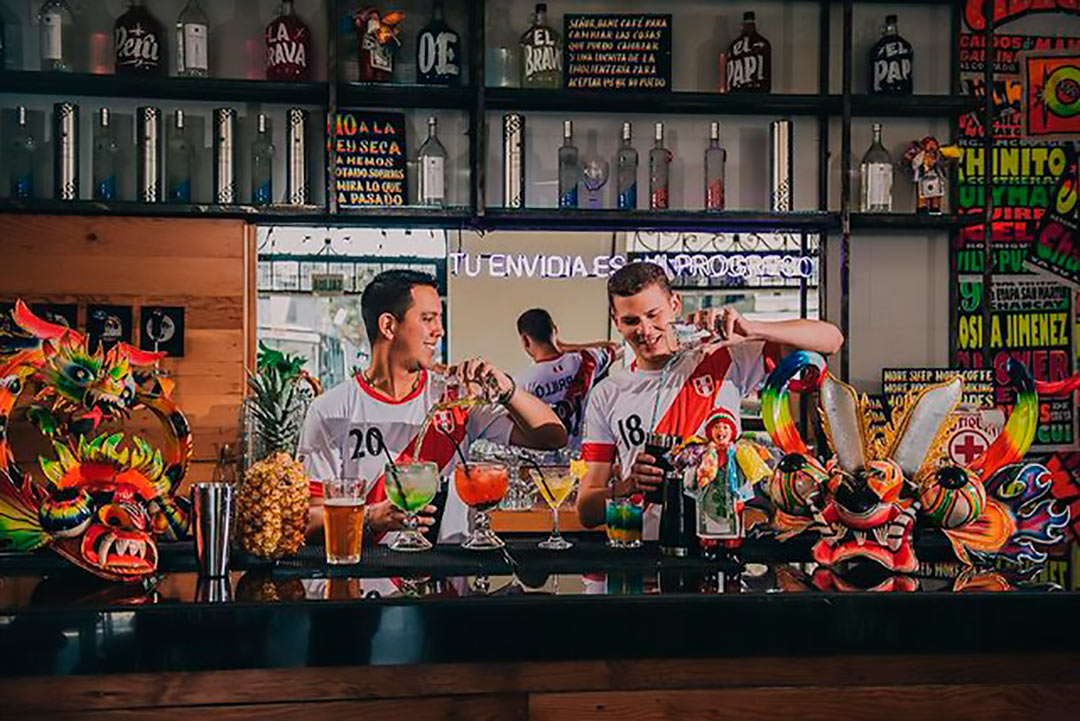 Dos jóvenes con la camiseta de Perú interactuan en La Emolientería Bar