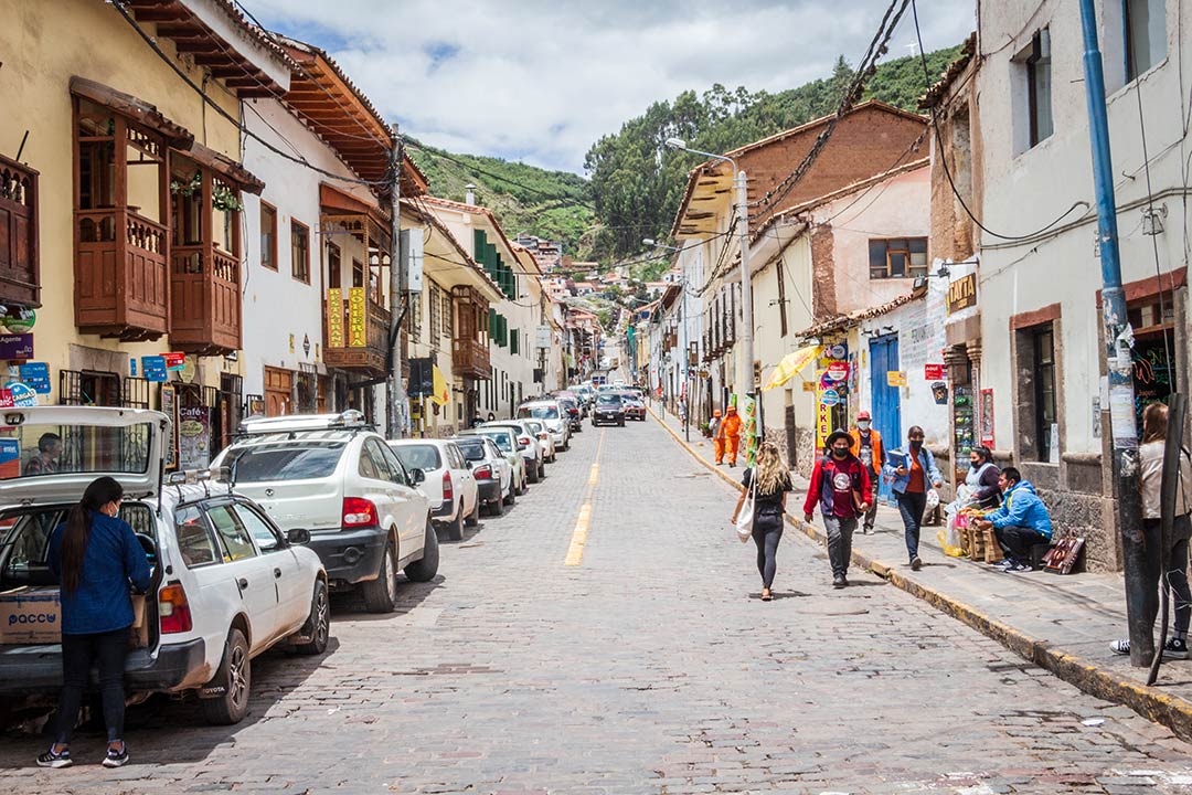 Vista diurna de la Calle Choquechaca, la gente camina desplazándose a sus hogares o trabajo. Hay autos estacionados a un costado de la calle.