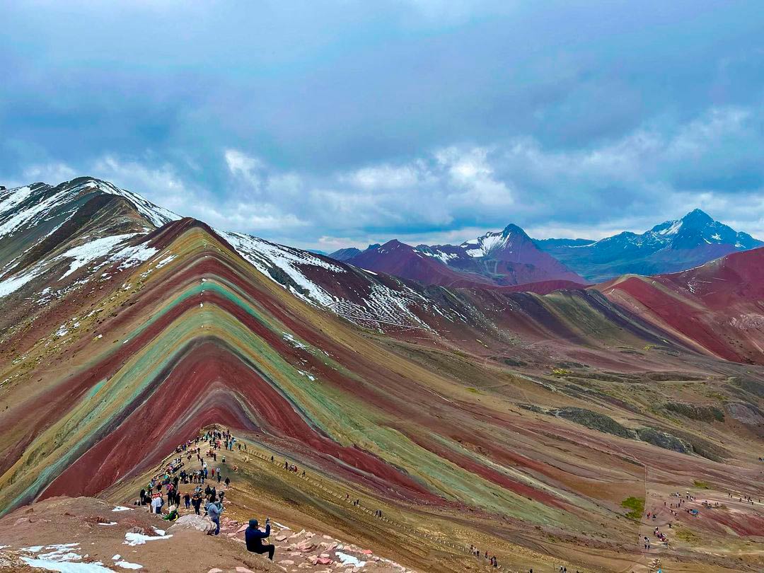 Hermosa vista de la montaña de siete colores, vinicunca o conocida internacionalmente como Rainbow Mountain. Es de día y la gente se ve entusiasta de llegar a este hermoso lugar. Se ve como la formación de la montaña de 7 colores fue impresionante.