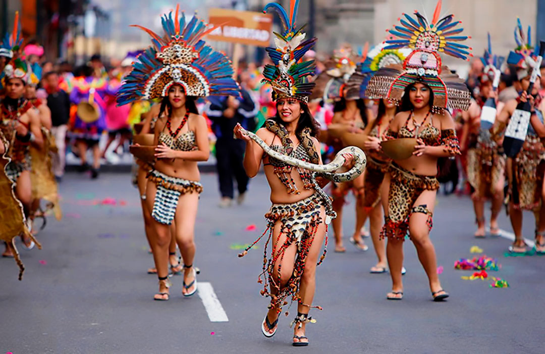 Personas en la calle, aparentemente en un pasacalle, haciendo la danza del orgullo shipibo