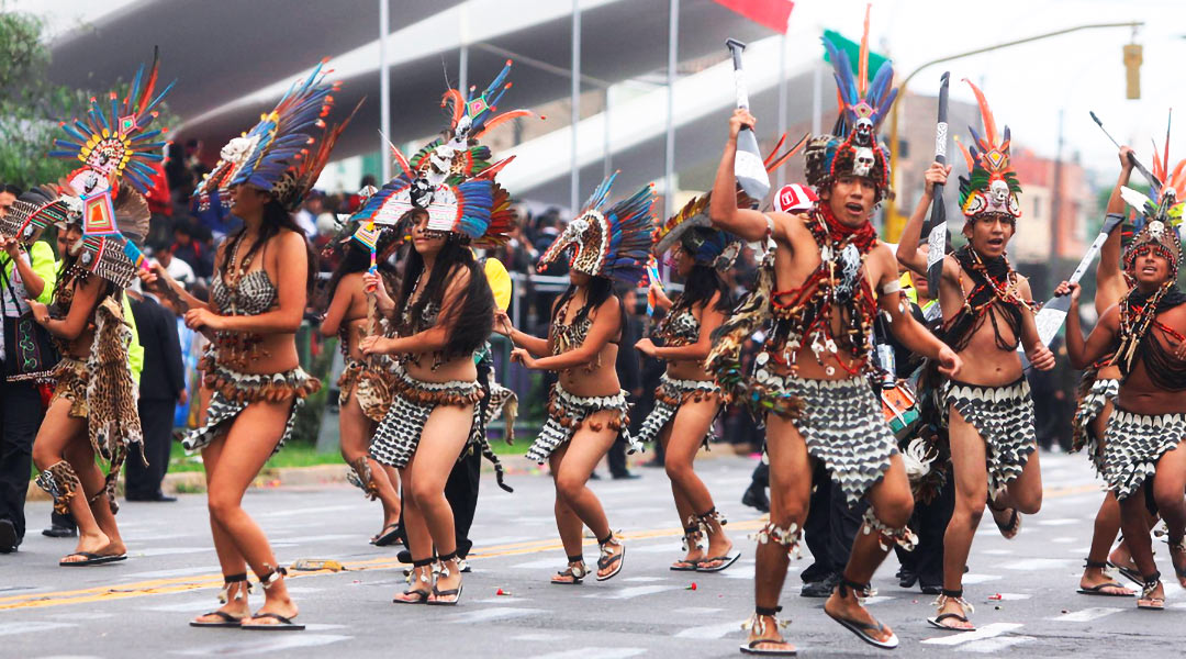 Vista de jóvenes bailando la Danza de la Boa, en medio de un desfile.