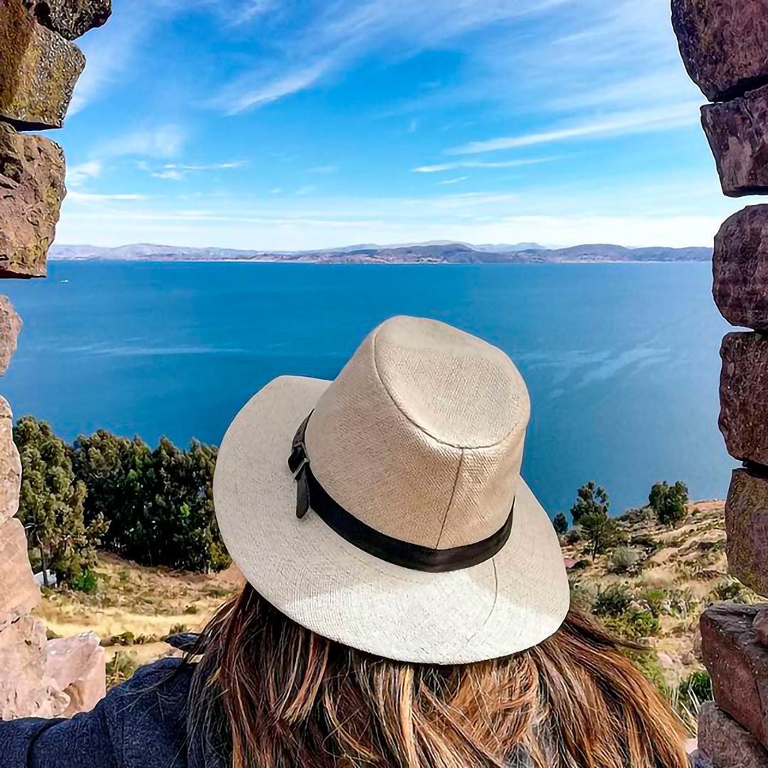 Joven con un sombrero blanco, contempla debajo de un arco antiguo las aguas del Titicaca, en la Isla Taquile